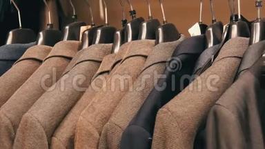 在商场的一家<strong>男士服装</strong>店，一排暖男`夹克衫在衣架上。 各种男士`西装挂在购物中心